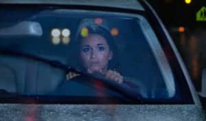 Young woman driving at night through a heavy rain storm.