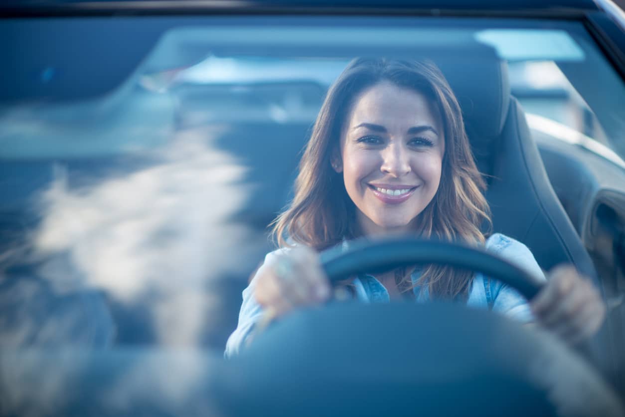 Happy woman driving a car and smiling