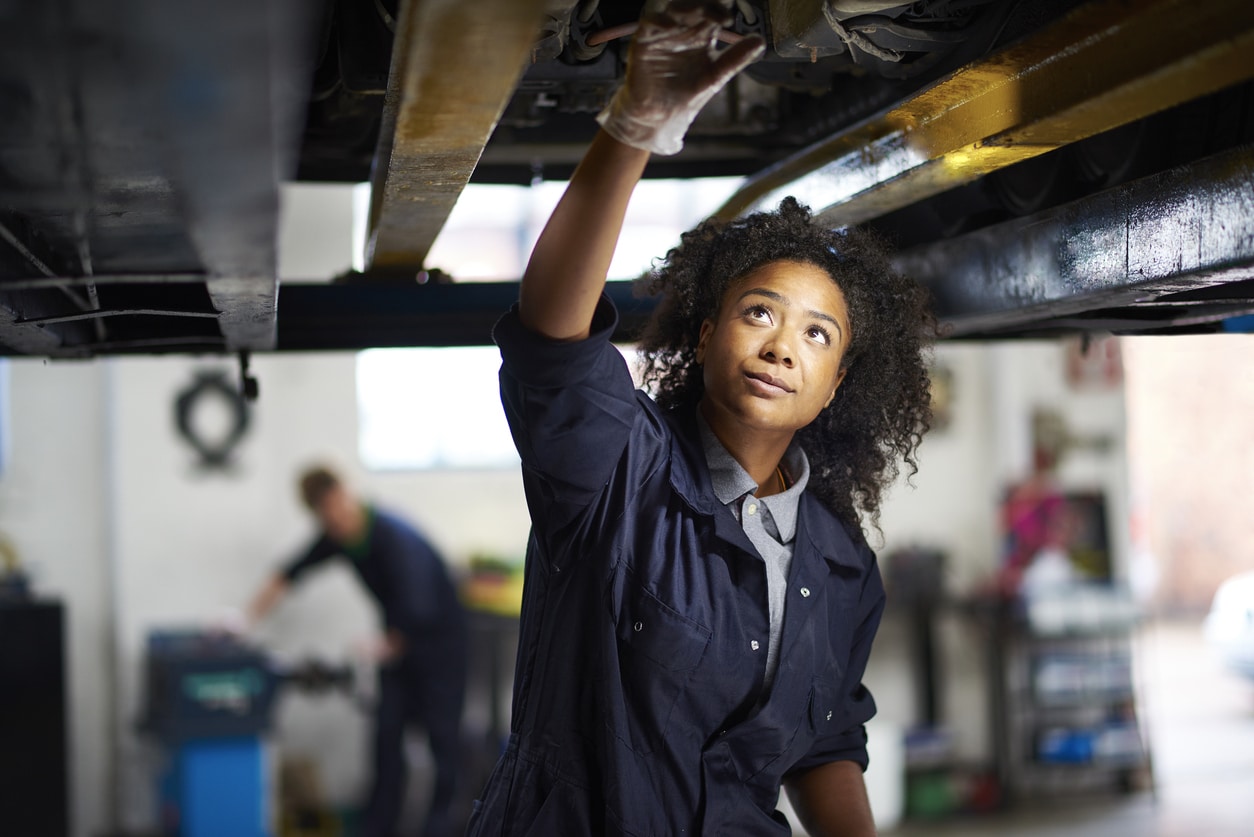 Women mechanic working under a car