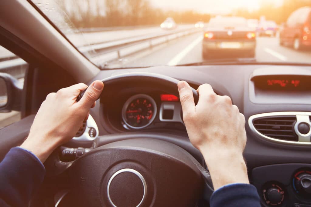 traffic jam, driving car on highway, close up of hands on steering wheel in sunny day