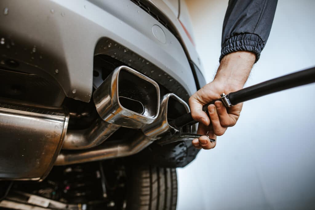 Mechanic checks exhaust in garage, vehicle inspection