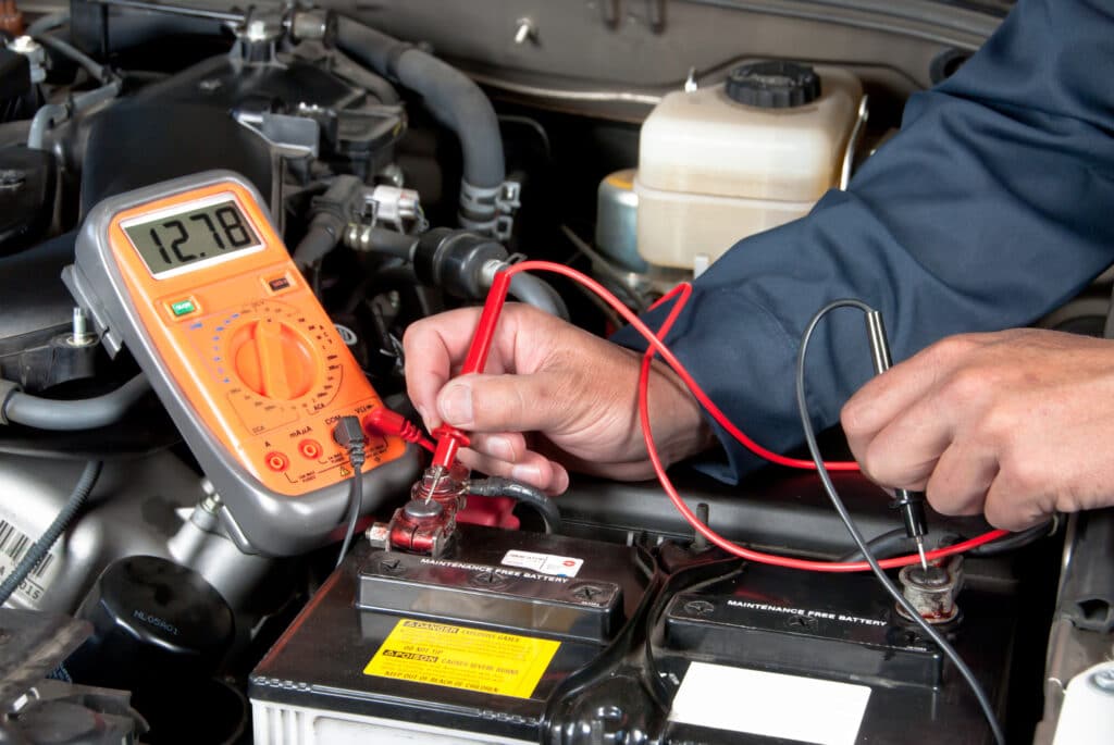 Cropped car mechanic hands testing a car battery