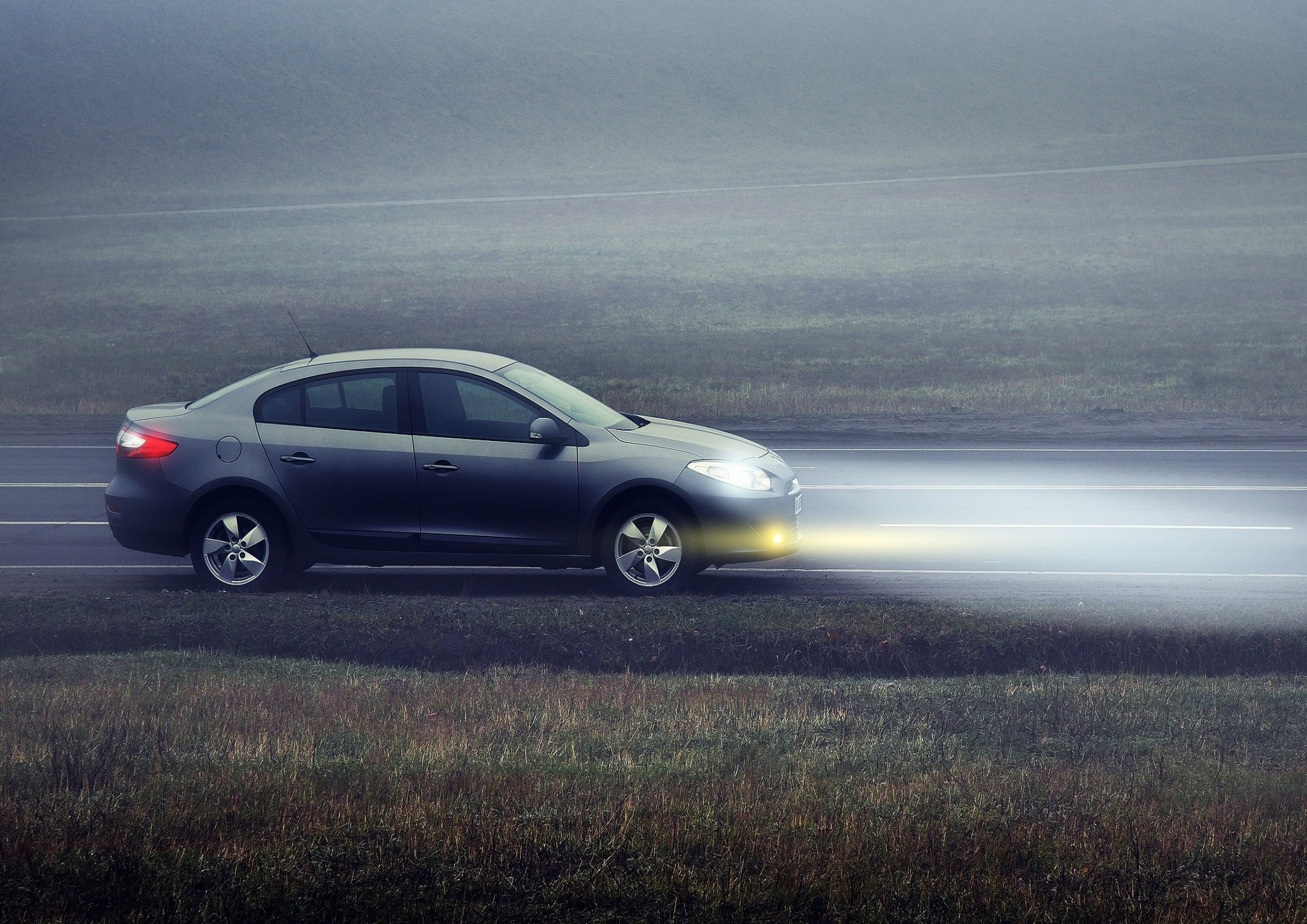 headlights lighting up a dark road in the winter