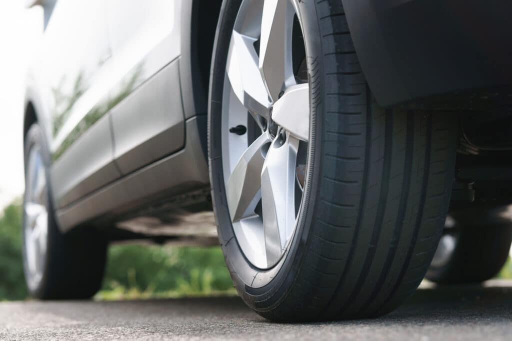 View of the new tires and modern aluminum trim of a parked SUV, shot from below, photo developed in raw format as a black and white image