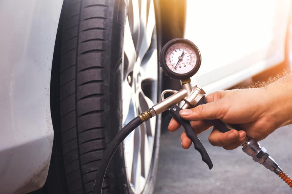 A auto mechanic inflates a tire with an air tire inflating gun in the auto repair garage